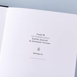 Close up of the open front page of Tsuki ‘Cup of Galaxy’ Limited Edition Holographic Bullet Journal on light blue background