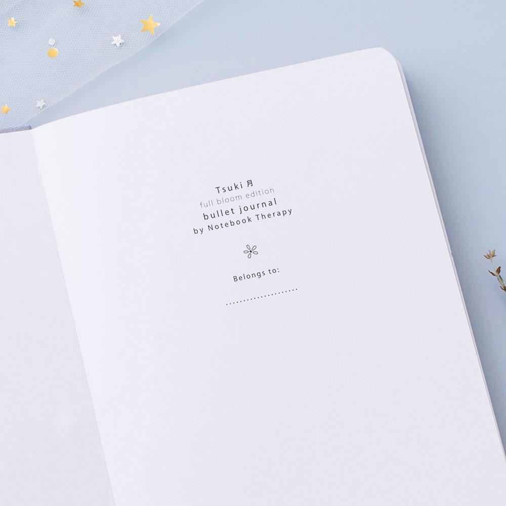 Close up of open front page of Tsuki ‘Full Bloom’ Limited Edition Bullet Journal on lilac background