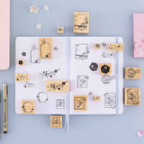 Tsuki ‘Sakura Journey’ Bullet Journal Stamps on open Tsuki ‘Sakura Journey’ Limited Edition Bullet Journal with pen and cherry blossom petals on light blue background