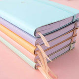 Tsuki Pastel Edition Bullet Journals in mint matcha and pink sakura and honey butter and lilac taro and bluebell stacked on pink background