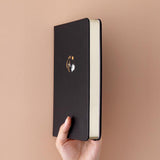 Tsuki ‘Moonlit Wish’ Limited Edition Bullet Journal held in hand at spine angle in light brown background