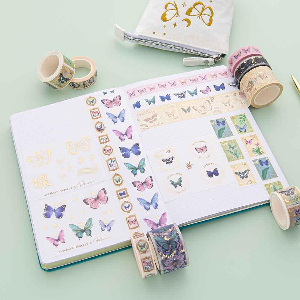 Tsuki ‘Flutter + Dream’ Washi Tape Set by Notebook Therapy x Pelinkan rolled out on open page spread of Tsuki Teal Sky ‘Flutter + Dream’ Limited Edition Bullet Journal by Notebook Therapy x Pelinkan with Tsuki ‘Flutter + Dream’ Pop-Up Pencil Case by Notebook Therapy x Pelinkan on mint background