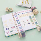 Tsuki ‘Flutter + Dream’ Washi Tape Set by Notebook Therapy x Pelinkan rolled out on open page spread of Tsuki Teal Sky ‘Flutter + Dream’ Limited Edition Bullet Journal by Notebook Therapy x Pelinkan with Tsuki ‘Flutter + Dream’ Pop-Up Pencil Case by Notebook Therapy x Pelinkan on mint background
