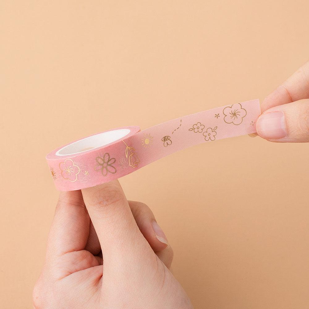 Tsuki Floral honey peach Washi tape rolled out in hands in peach background
