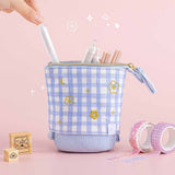 Tsuki ‘Sakura Journey’ Pop-Up Pencil Case with pens inside held in hands with Tsuki ‘Sakura Journey’ Washi Tape Set and Tsuki ‘Sakura Journey’ Bullet Journal Stamps in light pink background