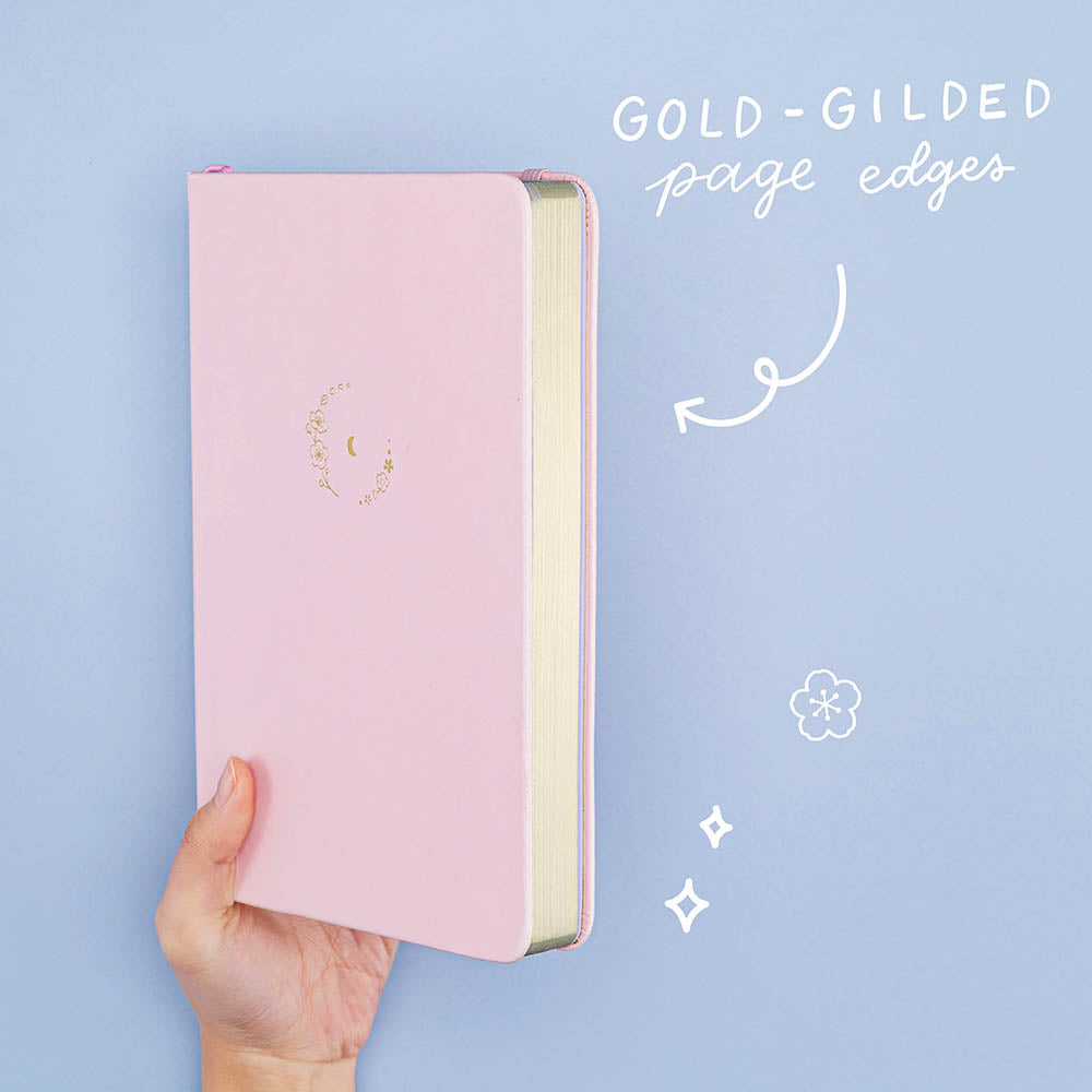 Tsuki ‘Lunar Blossom’ Limited Edition Bullet Journal held in hand at spine angle in light blue background