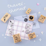 Travel themed Tsuki ‘Sakura Journey’ Bullet Journal Stamps on periwinkle and gingham envelopes with cherry blossom petals on light blue background