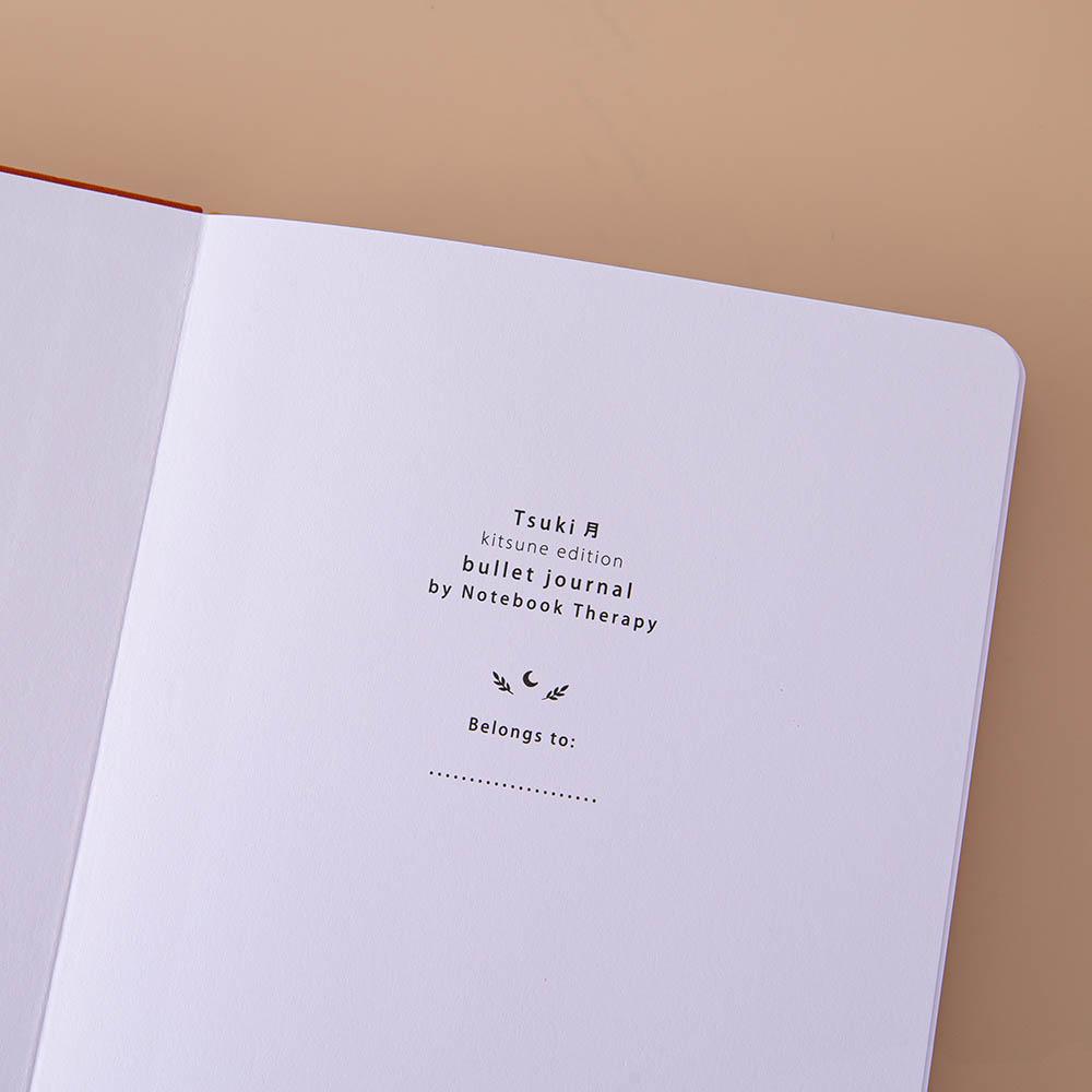 Close up of open front page of Tsuki ‘Kitsune’ Limited Edition Fox Bullet Journal on beige background