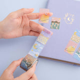 Tsuki ‘Moonflower’ Washi Stamp Tape held in hands with Tsuki ‘Full Bloom’ Limited Edition Bullet Journal on dusty blue background
