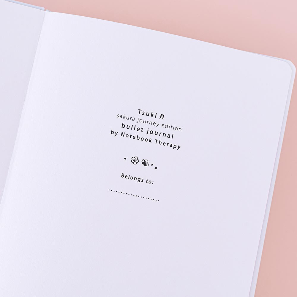 Close up of open front page of Tsuki ‘Sakura Journey’ Limited Edition Bullet Journal on pink background