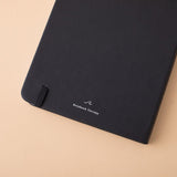 Close up of the back cover of deep black Tsuki Playful Orca limited edition bullet journal on peach background
