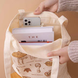 Open Tsuki ‘Vintage Kinoko’ Tote Bag with book and mobile phone and Tsuki ‘Kitsune’ Limited Edition Fox Bullet Journal inside held in hands in beige background