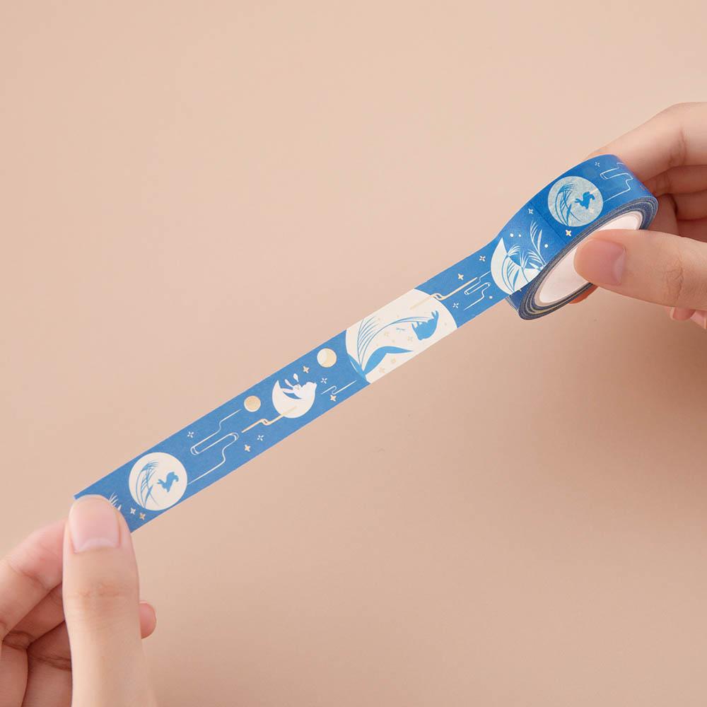 Tsuki ‘Moonlit Wish’ gold foil Washi Tape held in hands in light brown background