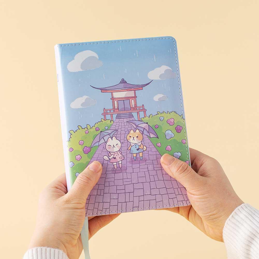Tsuki Four Seasons: Summer Edition Bullet Journal designed with @milkkoyo held in hands in honey yellow background