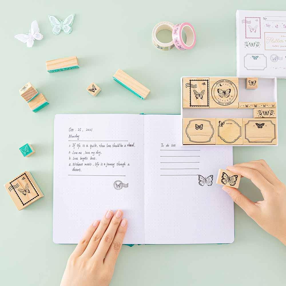 Tsuki ‘Flutter + Dream’ Bullet Journal Stamp Set by Notebook Therapy x Pelinkan held in hands on open Tsuki Teal Sky ‘Flutter + Dream’ Limited Edition Bullet Journal page spread on mint background