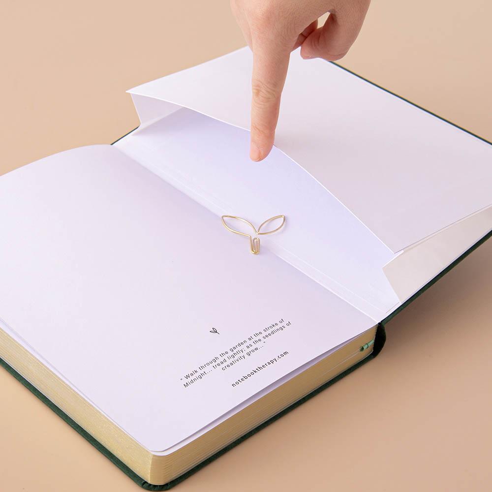 Open back page pocket of Tsuki ‘Midnight Garden’ Limited Edition Bullet Journal held in hand on beige background