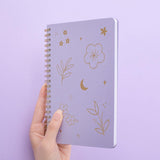 Tsuki lilac taro floral ringbound notebook held in hand at angle in lilac background
