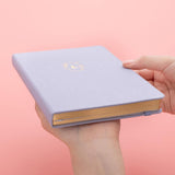 Tsuki ‘Full Bloom’ Limited Edition Bullet Journal held in hands at an angle in coral pink background