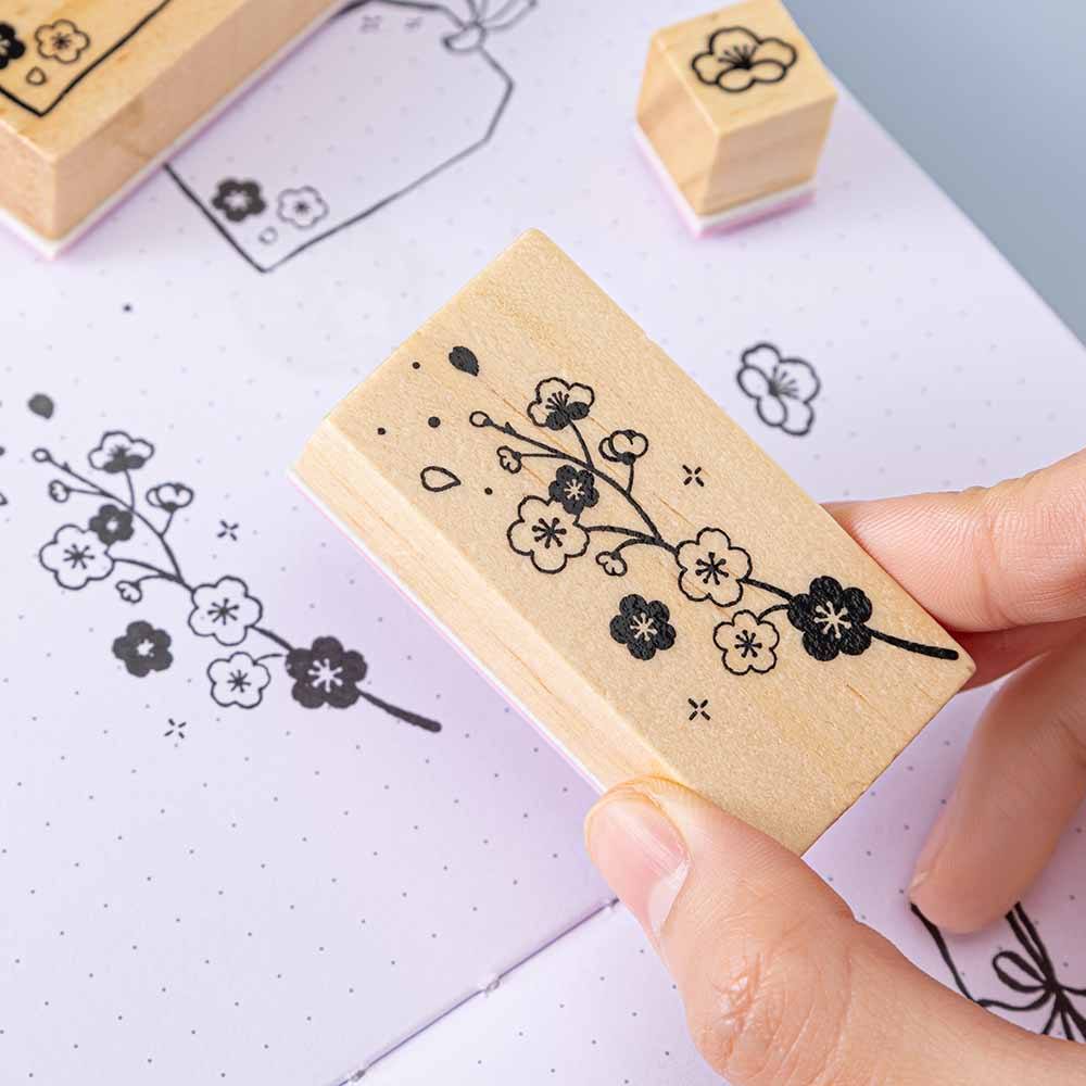 Close up of Tsuki ‘Sakura Journey’ Bullet Journal Stamp held in hand on open bullet journal page on light blue background
