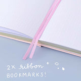 Close up of Tsuki ‘Lunar Blossom’ Limited Edition Bullet Journal with two bookmark ribbons on light blue background