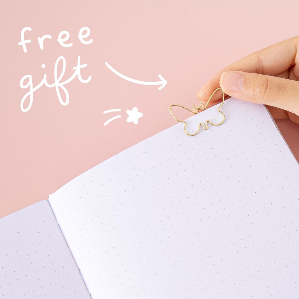 Close up of open page of Tsuki Cloud White ‘Flutter + Dream’ Limited Edition Bullet Journal by Notebook Therapy x Pelinkan with free butterfly bookmark gift held in hand in pastel pink background