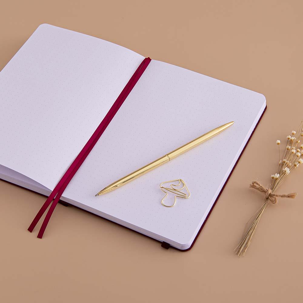 Open page spread of Tsuki ‘Kinoko’ Limited Edition Bullet Journal with free paperclip gift with gold pen and dried flowers on beige background