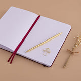 Open page spread of Tsuki ‘Kinoko’ Limited Edition Bullet Journal with free paperclip gift with gold pen and dried flowers on beige background