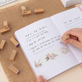 Tsuki Bullet Journal Typewriter Style Alphabet Stamps being used on open bullet journal with lettering on hessian mat on beige background