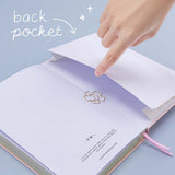 Open back page pocket of Tsuki ‘Lunar Blossom’ Limited Edition Bullet Journal with free bookmark gift held in hands in light blue background