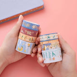 Tsuki ‘Moonflower’ Washi Stamp Tape Set held in hands with Tsuki ‘Full Bloom’ Limited Edition Bullet Journal on coral pink background