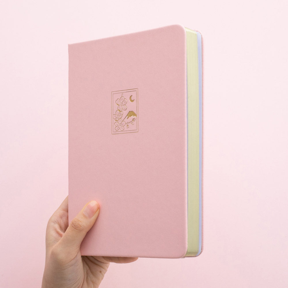 Tsuki 'Sakura' Limited Edition Bullet Journal in petal pink held in hand in light pink background