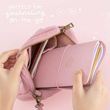 Tsuki ‘Sakura Journey’ Limited Edition Travel Notebook held in hands in Tsuki ‘Sakura Journey’ Travel Pouch in pink background