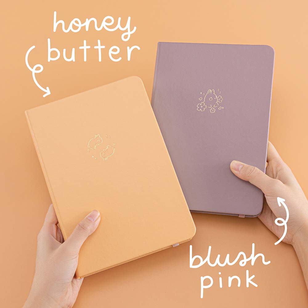 Tsuki Blush Pink ‘Bunny Blush’ Limited Edition Bullet Journal designed with Blossom Bujo with Tsuki Honey Butter ‘Bunny Blush’ Limited Edition Bullet Journal designed with Blossom Bujo held in hands in apricot background