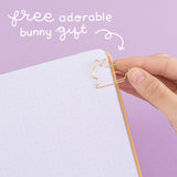 Close up of open Tsuki Honey Butter ‘Bunny Blush’ Limited Edition Bullet Journal designed with Blossom Bujo with free adorable bunny gift held in hand on lilac background