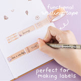 Functional writing tape from Tsuki Bunny Blush Washi Tape Set designed with Blossom Bujo rolled out on open bullet journal with pen held in hand on lilac background
