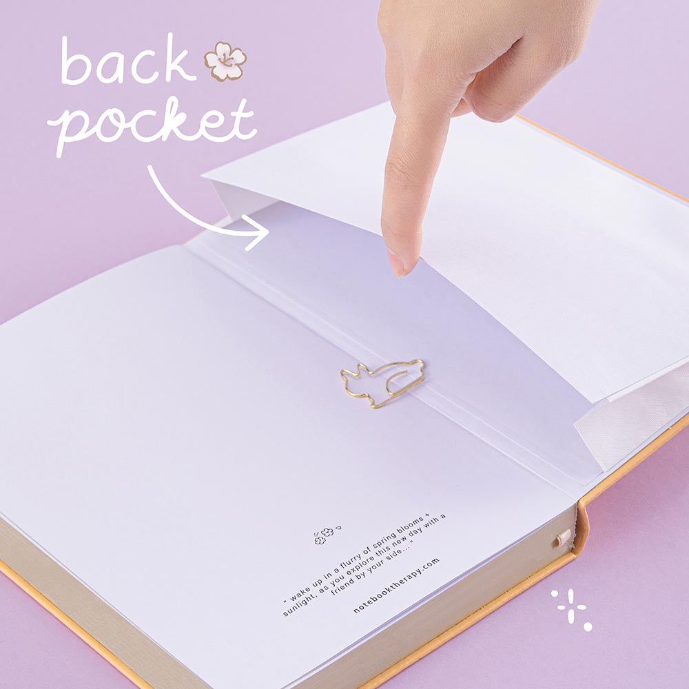 Open back page pocket of Tsuki Honey Butter ‘Bunny Blush’ Limited Edition Bullet Journal designed with Blossom Bujo held in hands in lilac background