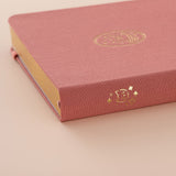 Close up of the gold details on the spine of a pink linen bullet journal