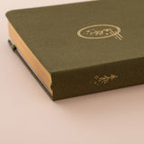 Close up of the gold details on the spine of a green linen bullet journal