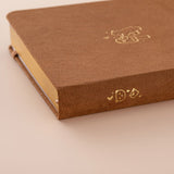 Close up of the gold details on the spine of a brown velvet bullet journal