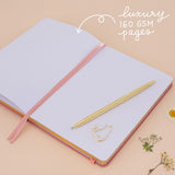 Notebook laid flat on beige background with the words ‘luxury 160gsm pages’ in white lettering