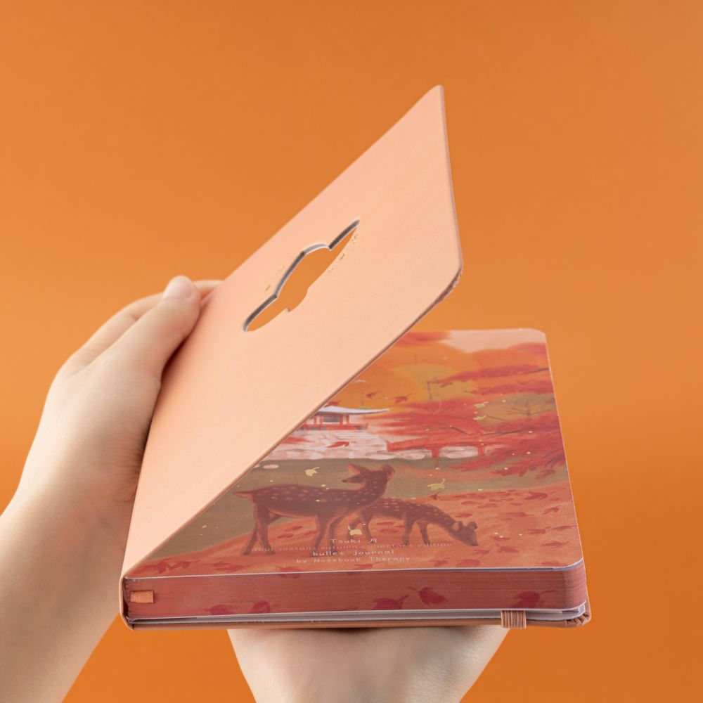 Hand holding Tsuki Four Seasons: Autumn Collector’s Edition 2022 Bullet Journal at an angle