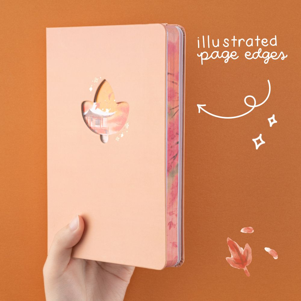 Hand holding Tsuki Four Seasons: Autumn Collector’s Edition 2022 Bullet Journal up with white text that says “illusteated page edges”