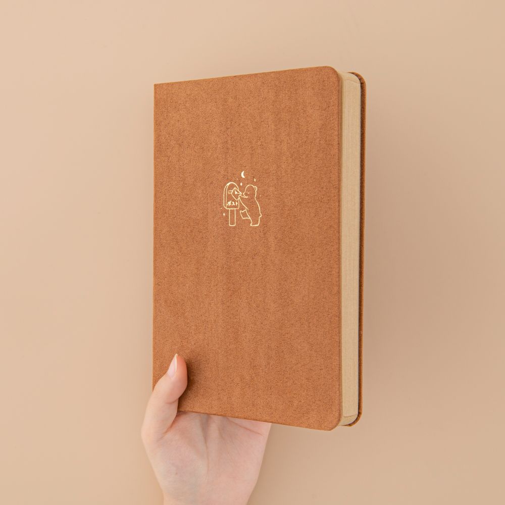Hand holding brown velvet bear bullet journal