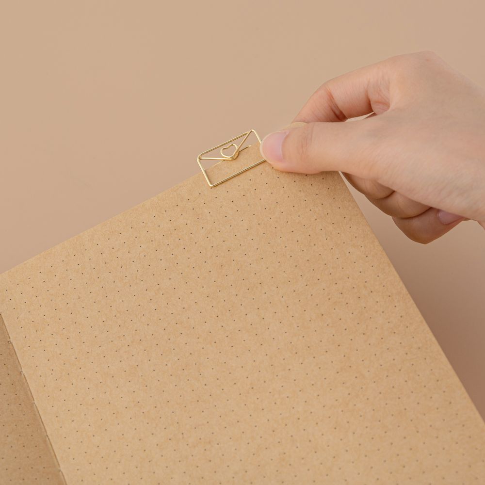 Love letter shaped paperclip on kraft paper page