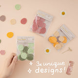 Hand holding green wax seal sticker set with pink wax seall sticker set and cream, yellow and brown in the background and 3x unique designs written in white