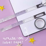 Write on label tape from Tsuki ‘Falling Star’ Washi Tape Set rolled out on open bullet journal page with stars on purple background