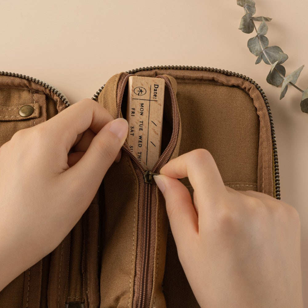 Hand zipping a pencil case with wooden stamp inside