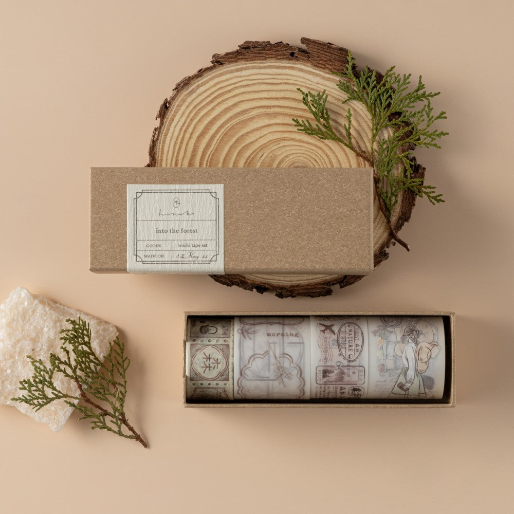 Hinoki Into the Forest PET + Washi Tape set opened box with the lid resting on a wood slice with a rock and pine leaves as decoration